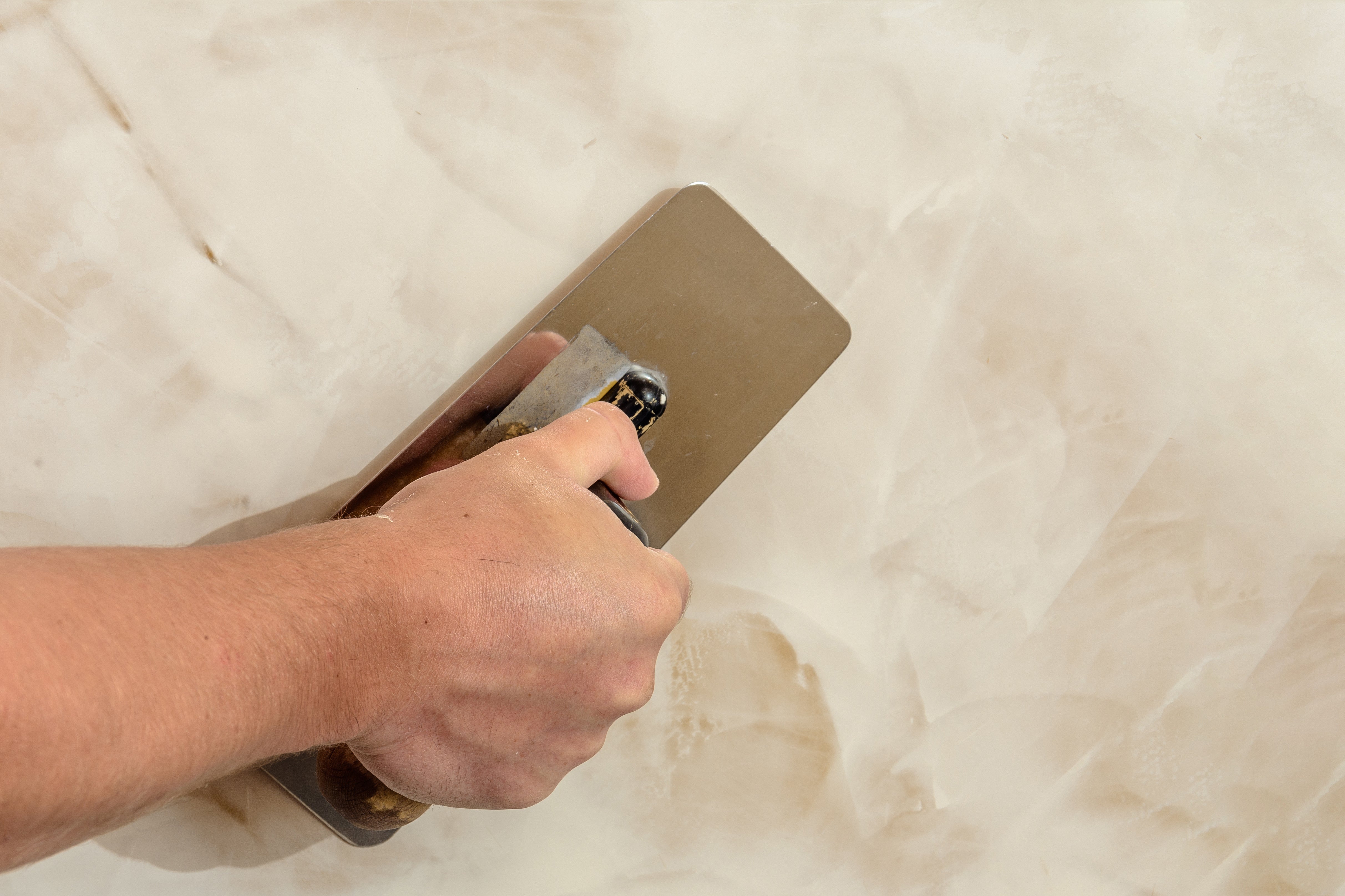 Applicator burnishing Venetian plaster with steel trowel to create polished lime finish