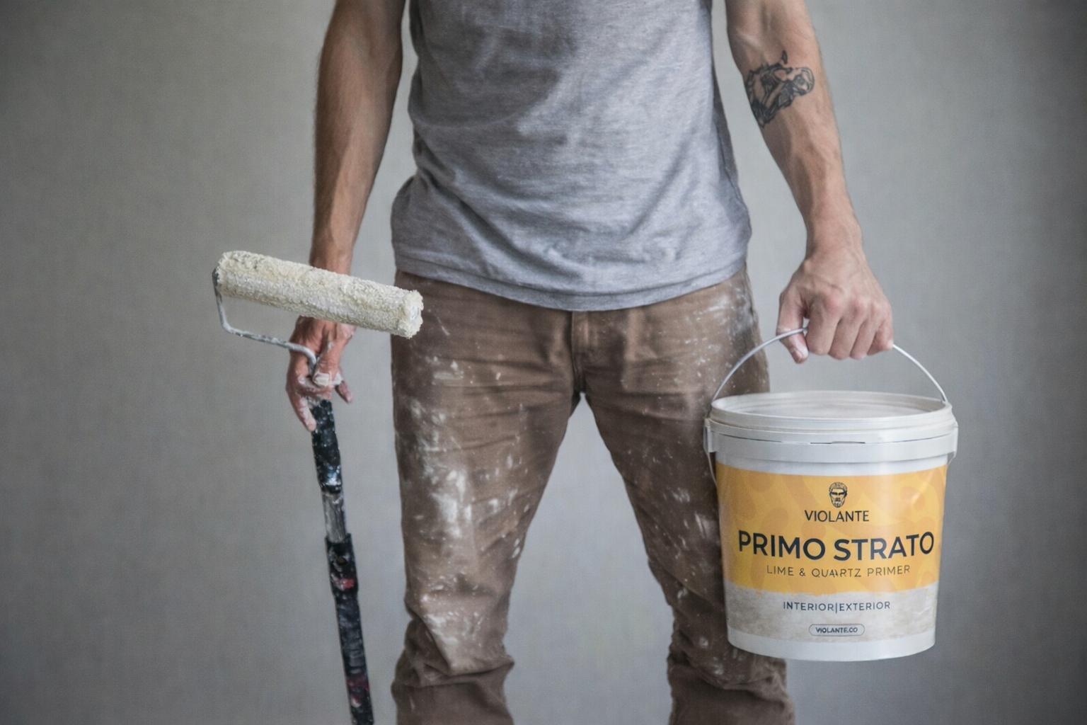 Professional Venetian plaster applicator holding VIOLANTE Primo Strato primer bucket and paint roller